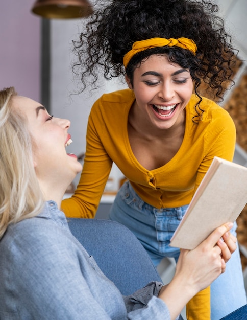 Due donne che ridono durante la lettura del libro