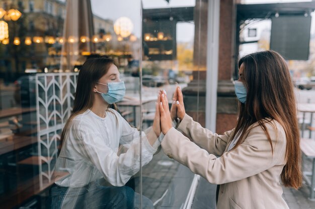 Due donne in maschere protettive una di fronte all'altra finestra tra di loro