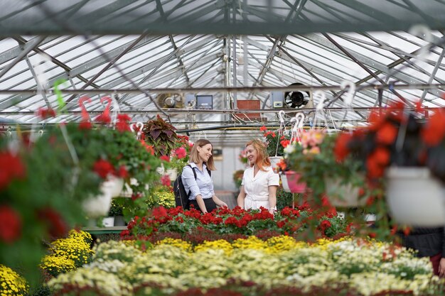 Due donne in posa in una serra tra centinaia di fiori