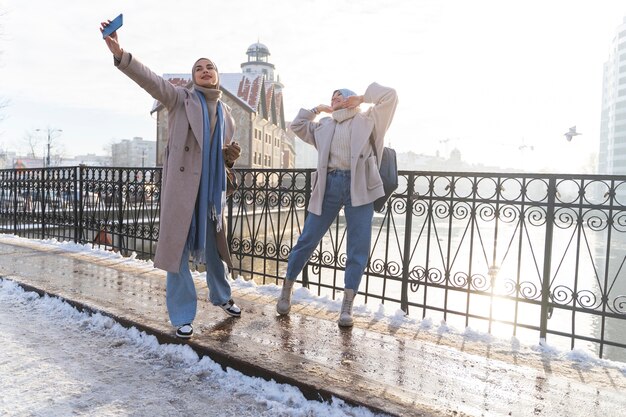 Due donne musulmane con l'hijab che si fanno un selfie mentre viaggiano in città