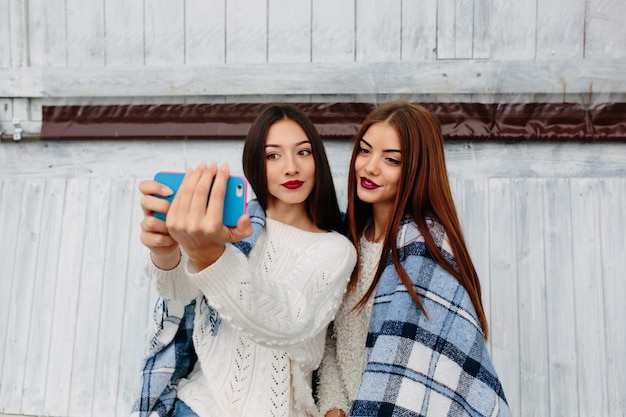 Due donne si siedono in panchina e fanno selfie