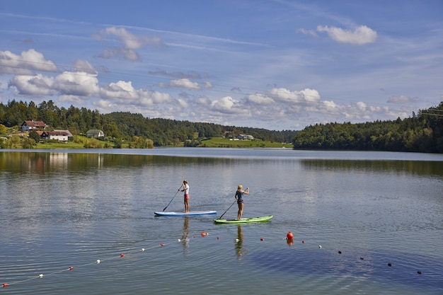 Due femmine in sella a uno stand up paddle board nel lago Smartinsko in Slovenia