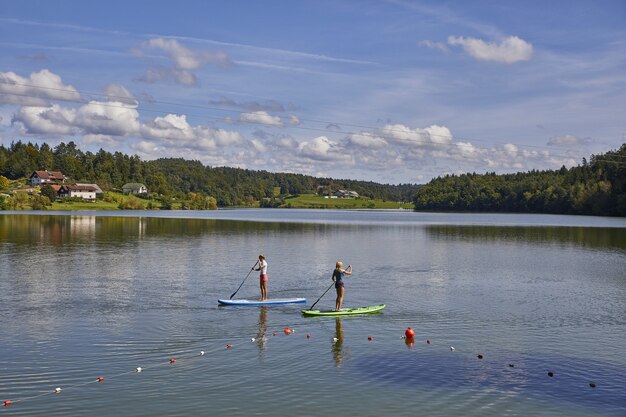 Due femmine in sella a uno stand up paddle board nel lago Smartinsko in Slovenia