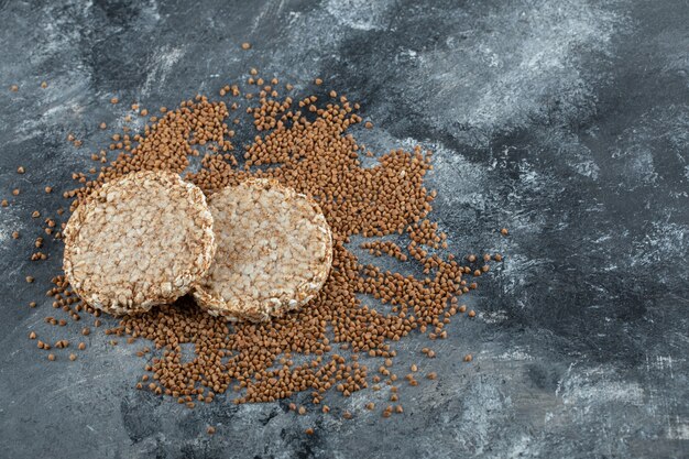 Due fette biscottate e grano saraceno crudo sulla superficie di marmo