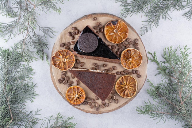 Due fette di torta con fette d'arancia e chicchi di caffè su un pezzo di legno. Foto di alta qualità