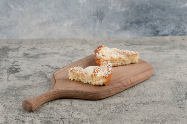 Due fette di torta con granelli di cocco su tavola di legno.