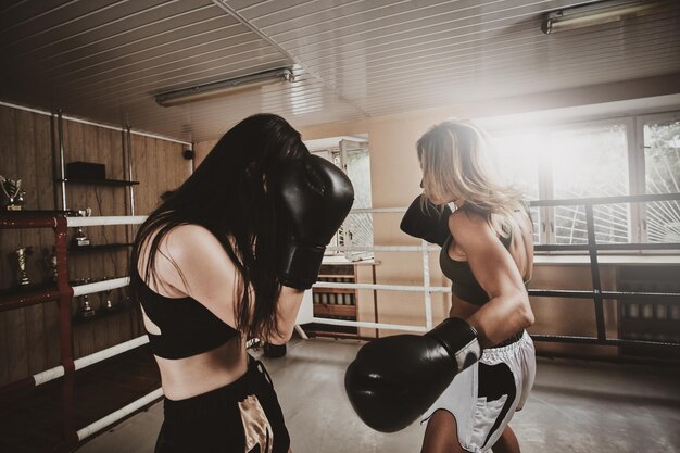 Due forti pugili femmine hanno uno sparring sul ring indossando guanti da boxe.