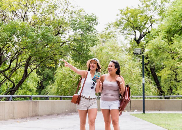 Due giovane turista femminile che cammina nel parco che osserva via