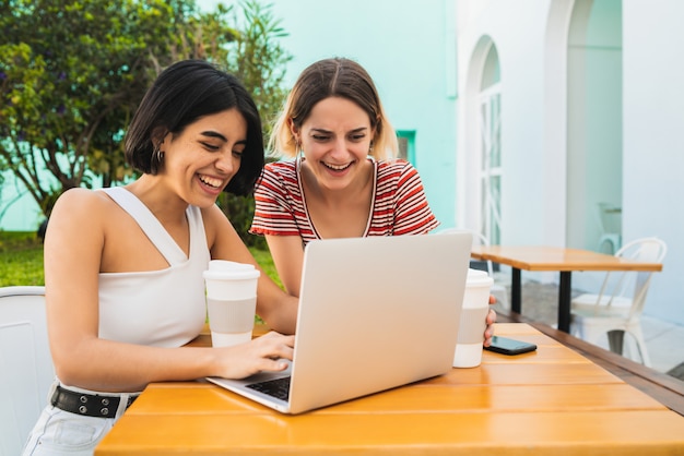 Due giovani amici che utilizzano un computer portatile presso la caffetteria.