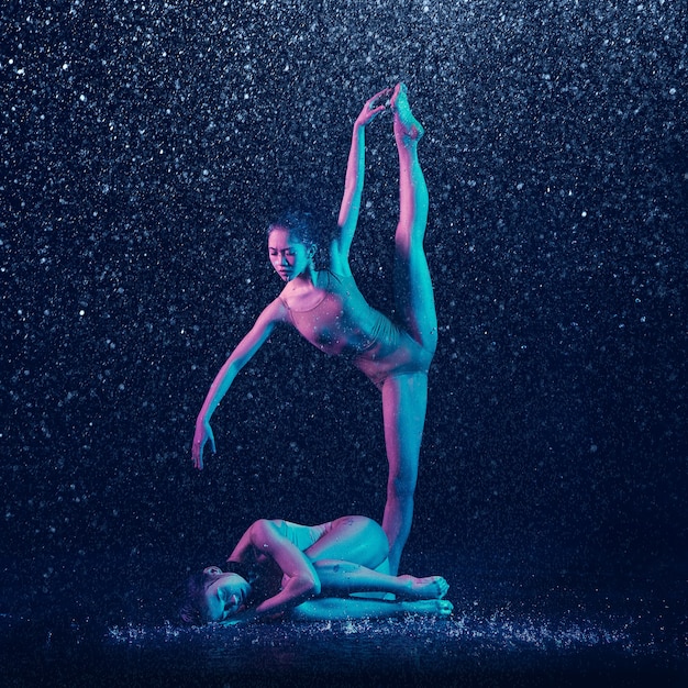 Due giovani ballerini femminili sotto le gocce d'acqua
