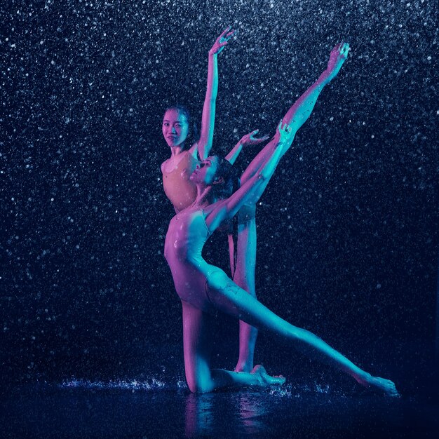 Due giovani ballerini femminili sotto le gocce d'acqua