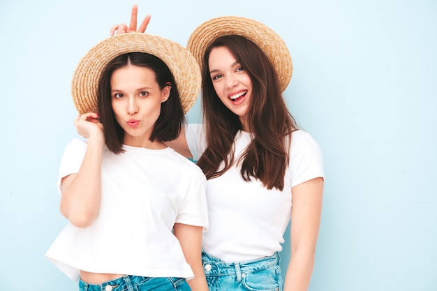 Due giovani belle donne hipster sorridenti in t-shirt bianca estiva alla moda e vestiti di jeans