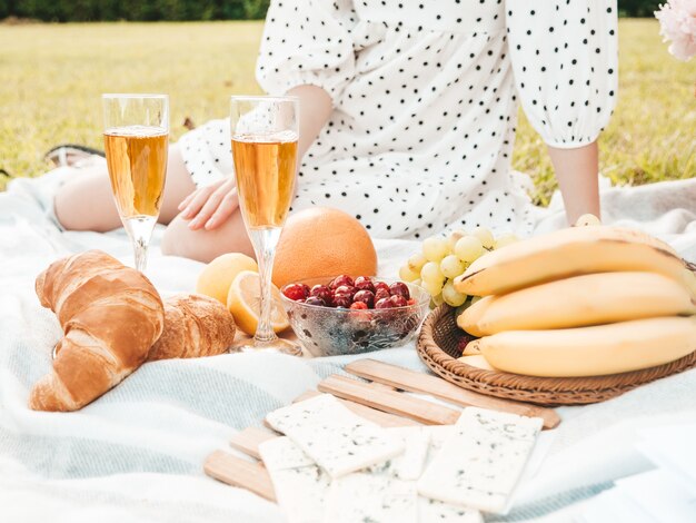 Due giovani belle donne sorridenti hipster in prendisole e cappelli estivi. Donne spensierate che fanno picnic all'esterno.