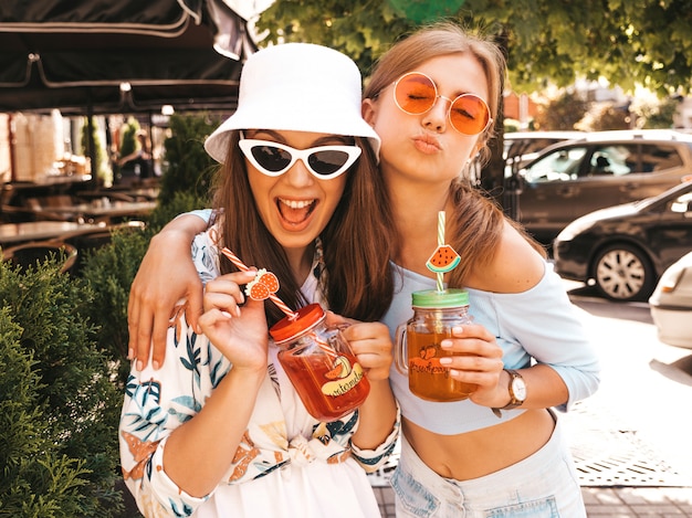 Due giovani belle ragazze sorridenti hipster in abiti estivi alla moda e cappello panama.