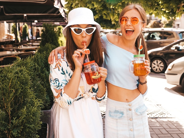 Due giovani belle ragazze sorridenti hipster in abiti estivi alla moda e cappello panama.