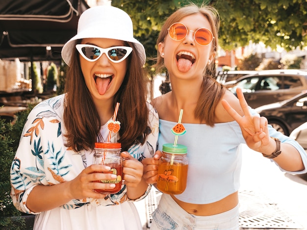 Due giovani belle ragazze sorridenti hipster in abiti estivi alla moda e cappello panama.