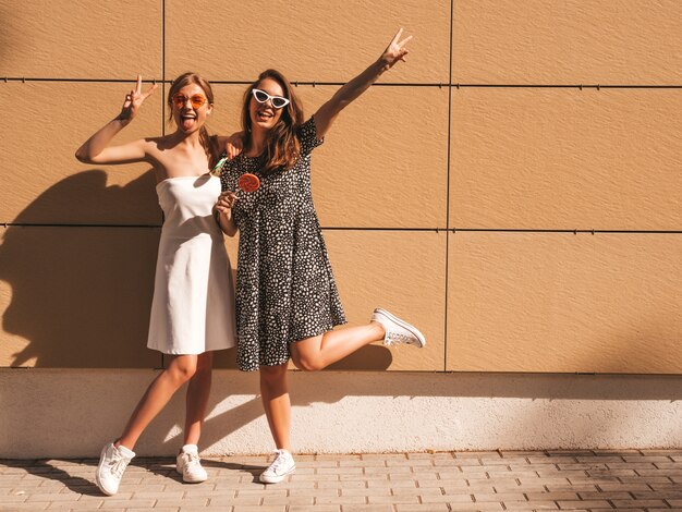 Due giovani belle ragazze sorridenti hipster in abito estivo alla moda.