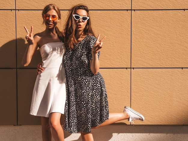 Due giovani belle ragazze sorridenti hipster in abito estivo alla moda.