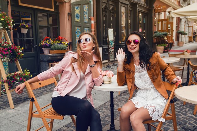 Due giovani donne alla moda che si siedono al caffè