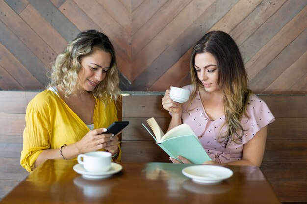 Due giovani donne attraenti che bevono caffè e che riposano in caffè