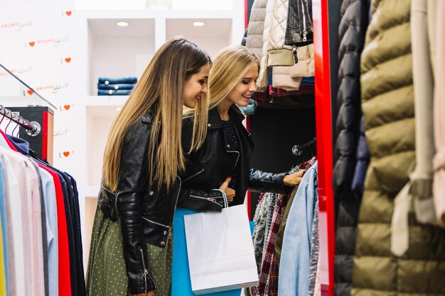 Due giovani donne bionde che esaminano i vestiti nel negozio di acquisto