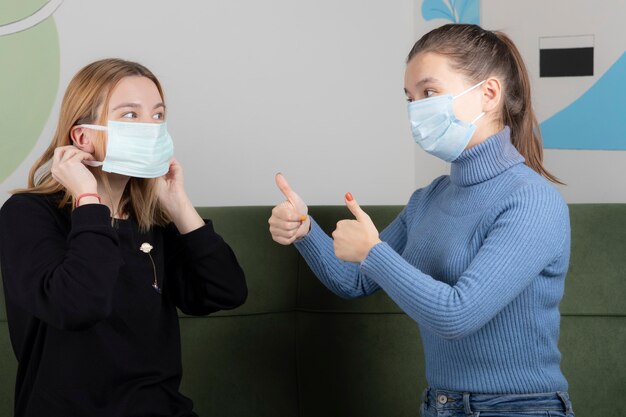 Due giovani donne con le mascherine si dicono che tutto andrà bene.