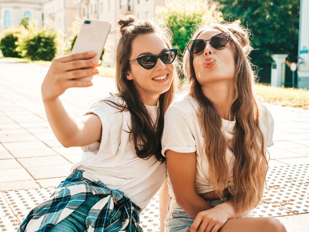 Due giovani donne hipster sorridenti in abiti estivi