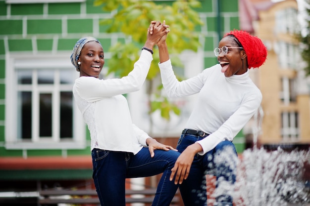 Due giovani donne musulmane africane attraenti moderne alla moda alte e magre in hijab o sciarpa a turbante poste insieme