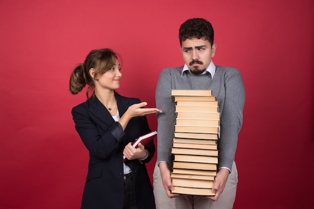 Due giovani persone di affari con i libri che fissano a vicenda