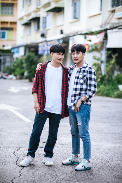 Due giovani uomini amorevoli in camicie e in piedi sulla strada.