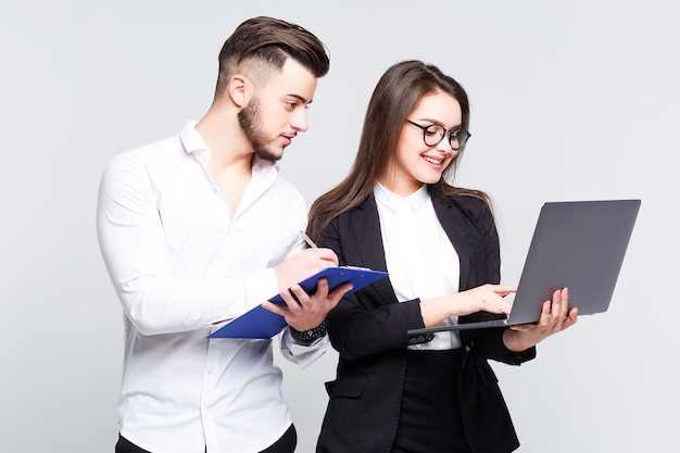 Due giovani uomini d'affari di successo sorridenti felici che lavorano con il computer portatile sulla parete bianca