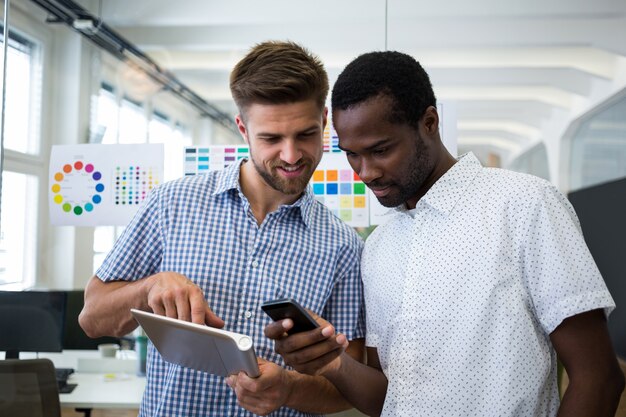 Due grafici maschi con tavoletta digitale e telefono cellulare