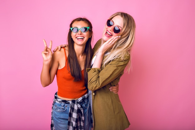 Due migliori amiche positive divertendosi indossando occhiali da sole