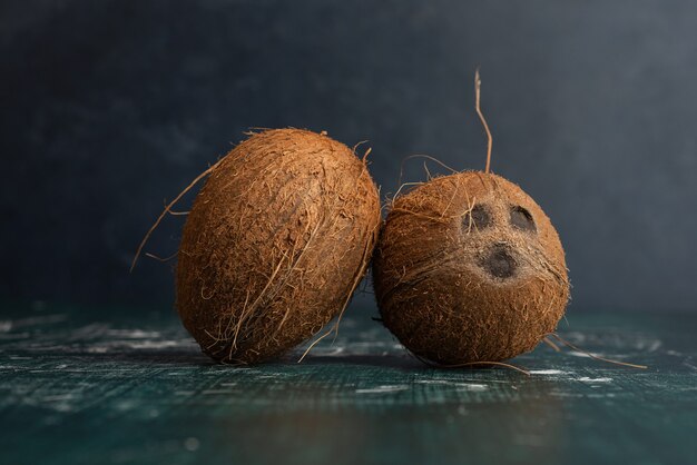 Due noci di cocco intere sulla tavola di marmo.