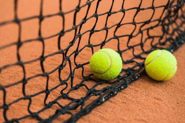 Due pallina da tennis vicino alla rete nera su terra