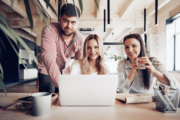 Due partner commerciali femminili e uno maschile che guardano lo schermo del computer e discutono del loro progetto