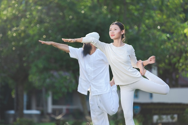 Due persone in abito bianco che fanno yoga in natura