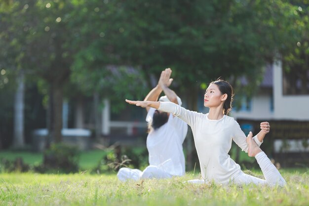 Due persone in abito bianco che fanno yoga in natura