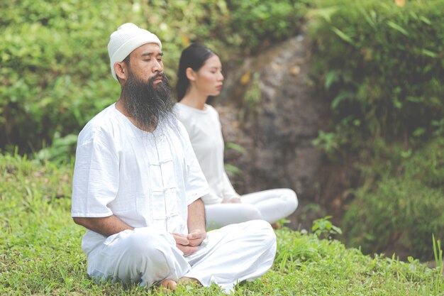 Due persone in abito bianco meditando nella natura