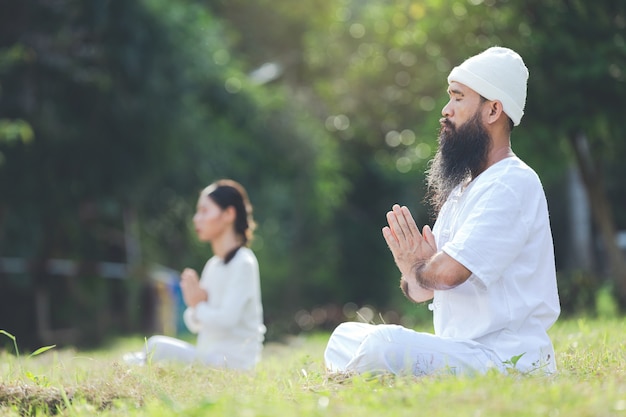 Due persone in abito bianco meditando nella natura