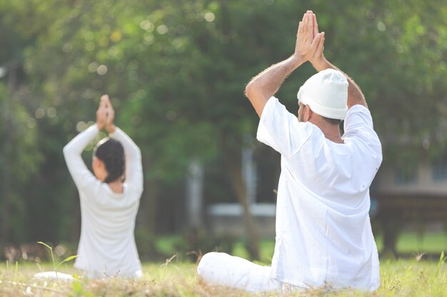 Due persone in abito bianco meditando nella natura