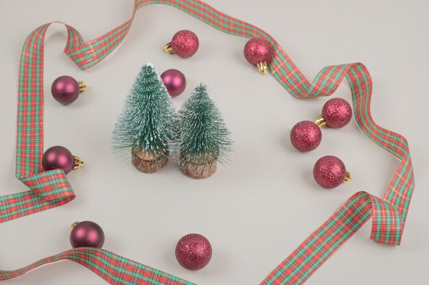 Due piccoli alberi di Natale con fiocco festivo sulla superficie bianca
