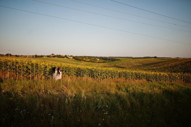 Due piuttosto giovani amici neri donna indossano abiti estivi posano in un campo di girasoli