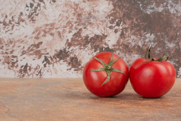 Due pomodori freschi isolati sulla tavola di marmo.