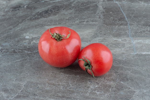 Due pomodori freschi, sul tavolo di marmo.