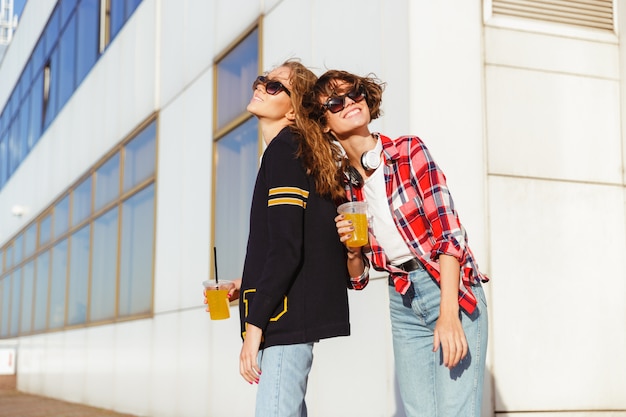 Due ragazze allegre nel bere occhiali da sole