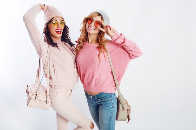 Due ragazze beate in abito alla moda rosa in posa in studio