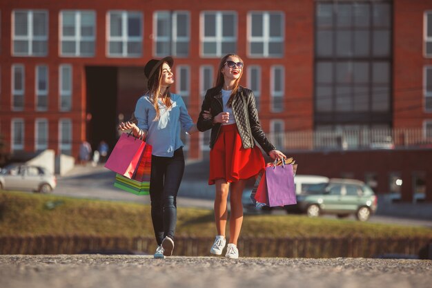 Due ragazze che camminano con i sacchetti della spesa sulle vie della città al giorno soleggiato