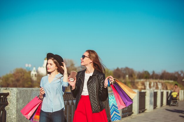 Due ragazze che camminano con i sacchetti della spesa sulle vie della città al giorno soleggiato