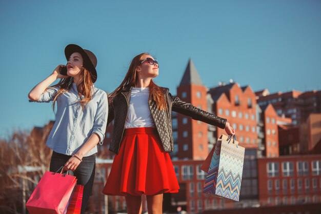 Due ragazze che camminano con i sacchetti della spesa sulle vie della città al giorno soleggiato